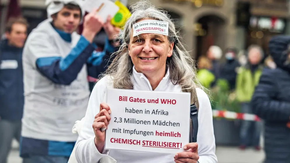 Anti-Corona-Verschwörung Eine Demonstrantin hat ein Schild auf der Stirn, auf dem steht, dass sie eine Impfpflicht ablehnt.