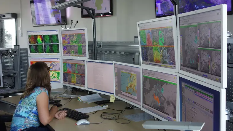 Wetterdienst-Mitarbeiterin sitzt vor mehreren Bildschirmen