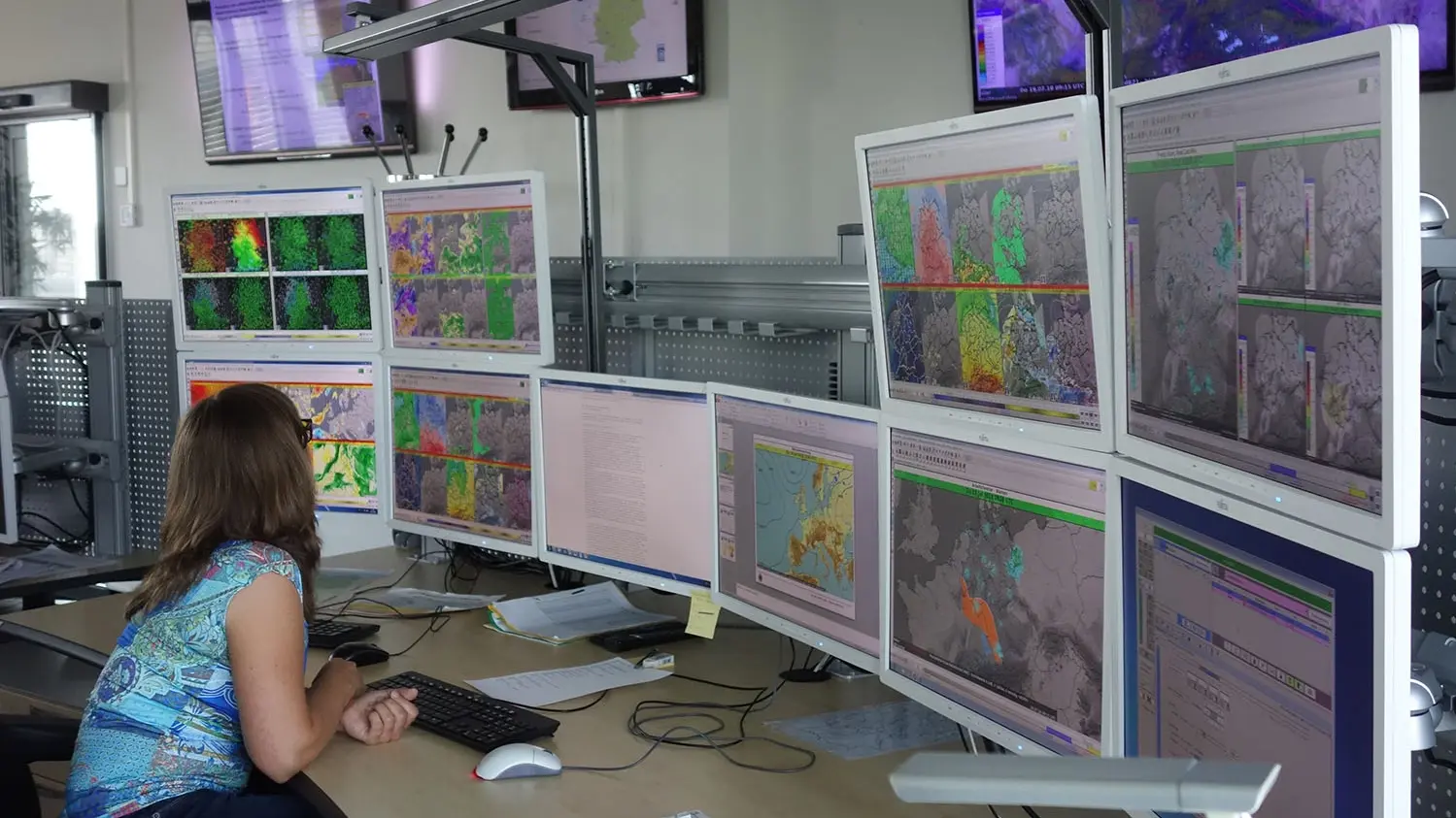 Wetterdienst-Mitarbeiterin sitzt vor mehreren Bildschirmen