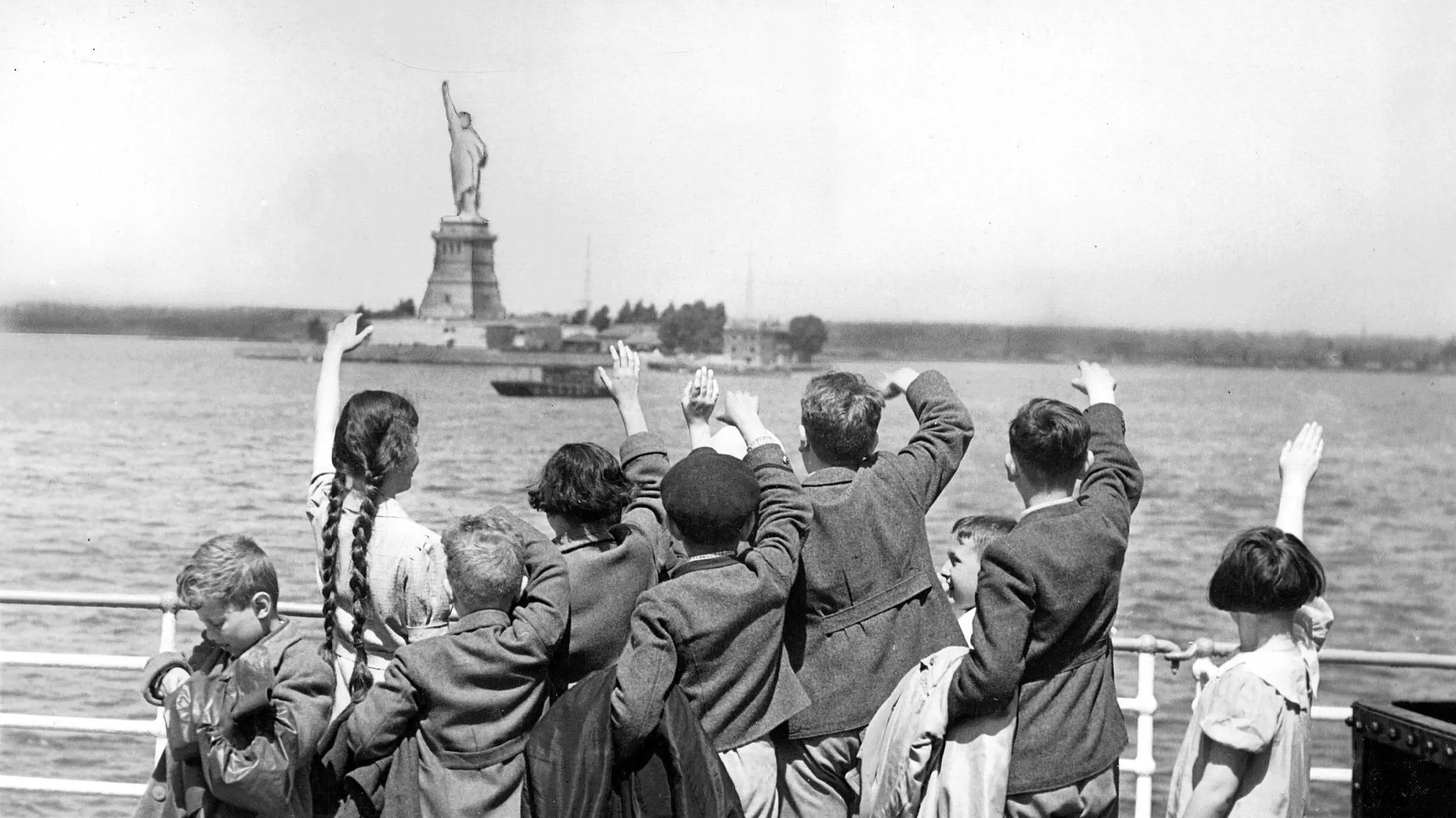 Jüdische Kinder aus Wien winken bei ihrer Ankunft im Juni 1939 in New York der Freiheitsstatue zu Jüdische Kinder aus Wien winken bei ihrer Ankunft mit dem Passagierschiff "S.S. Präsident Harding" am 3. Juni 1939 in New York der Freiheitsstatue zu.