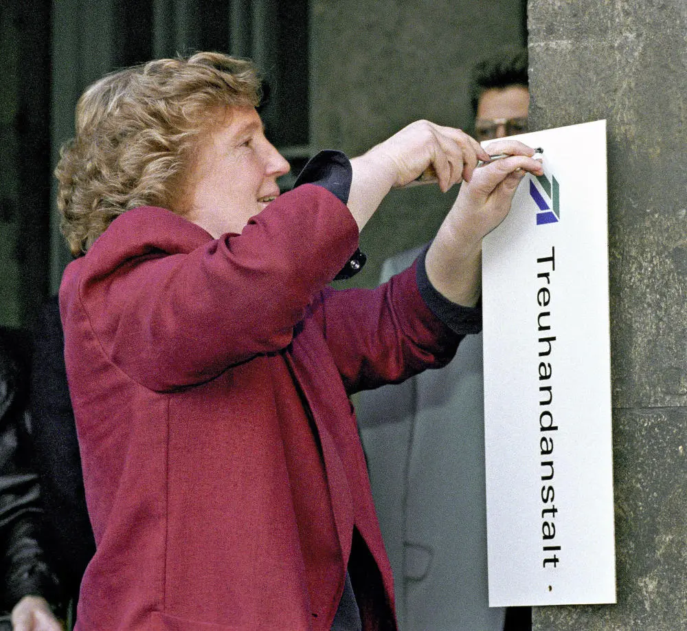 Birgit Breul schraubt ein Schild mit der Aufschrift Treuhandanstalt ab. Treuhandzentrale ab.