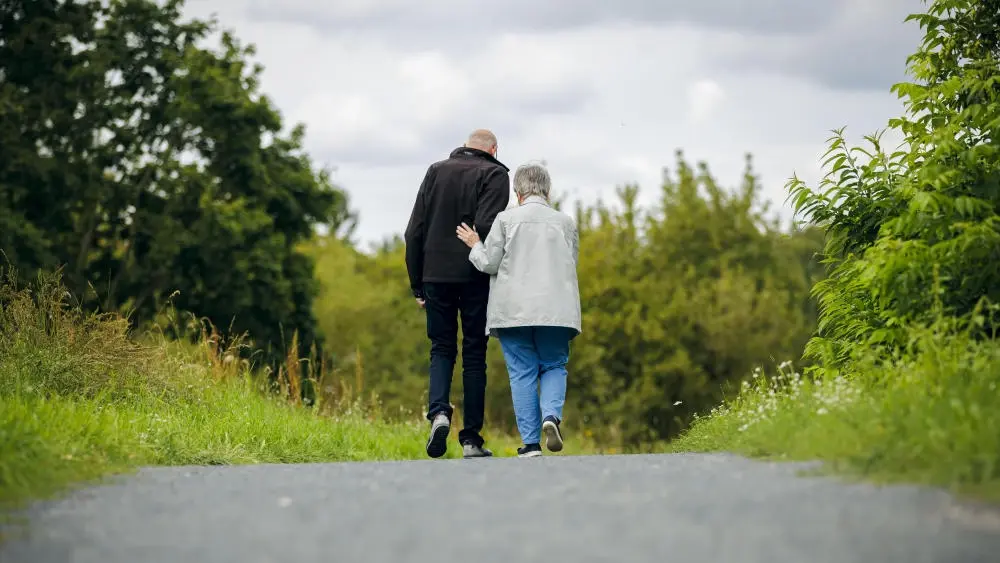 Auf dem Bild ist ein Seniorenpaar beim Spaziergang zu sehen.  