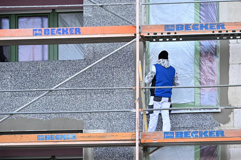 Auf eine Fassade eines Neubauhauses wird eine Dämmschicht aufgesetzt.
