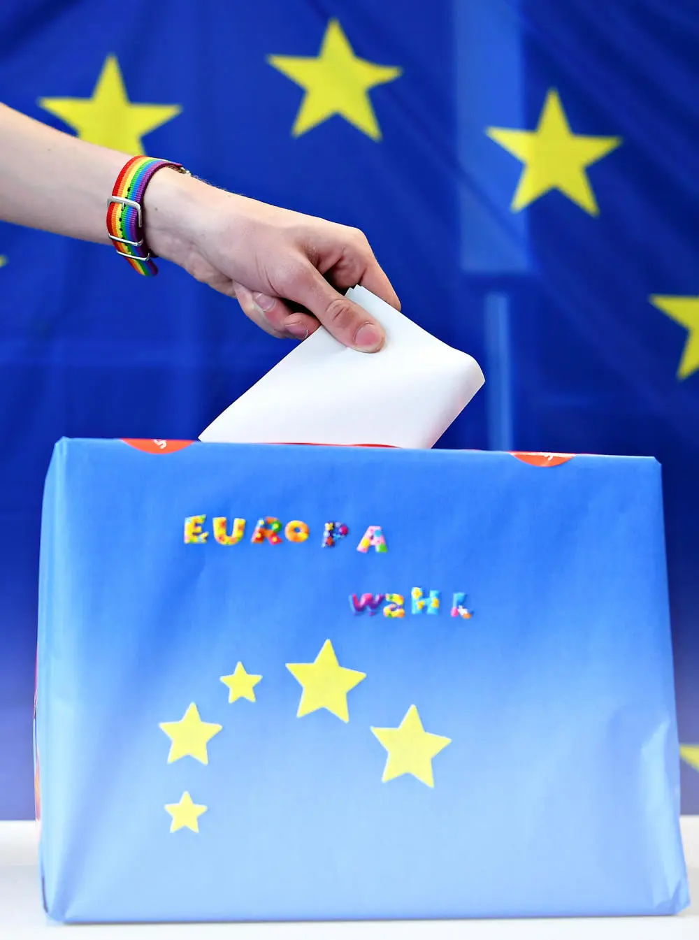 Wahlzettel wird in eine Wahlurne mit den EU-Sternen gesteckt 