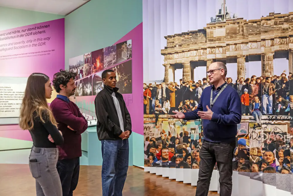 Drei Besucher des Deutschen Historischen Museums mit einem Mitarbeiter
