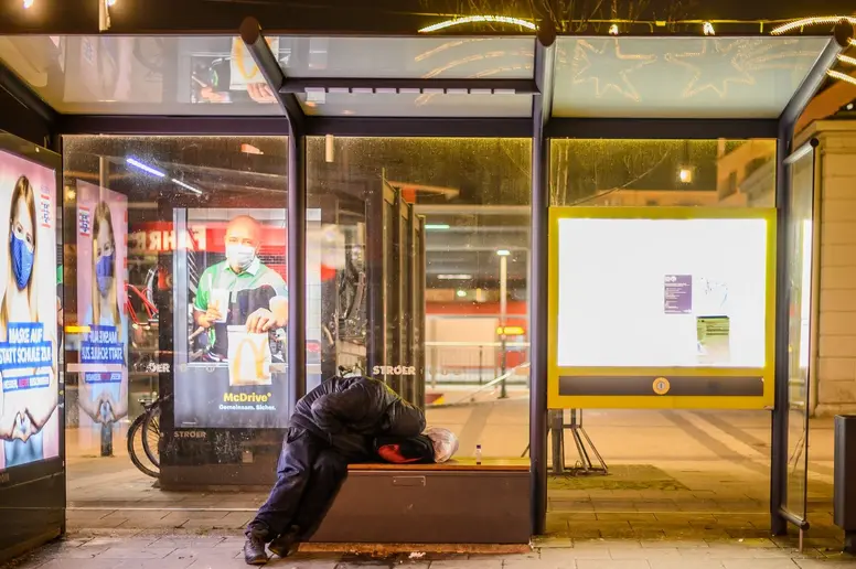 Ein Mensch übernachtet auf der Bank einer Berliner Bushaltestelle