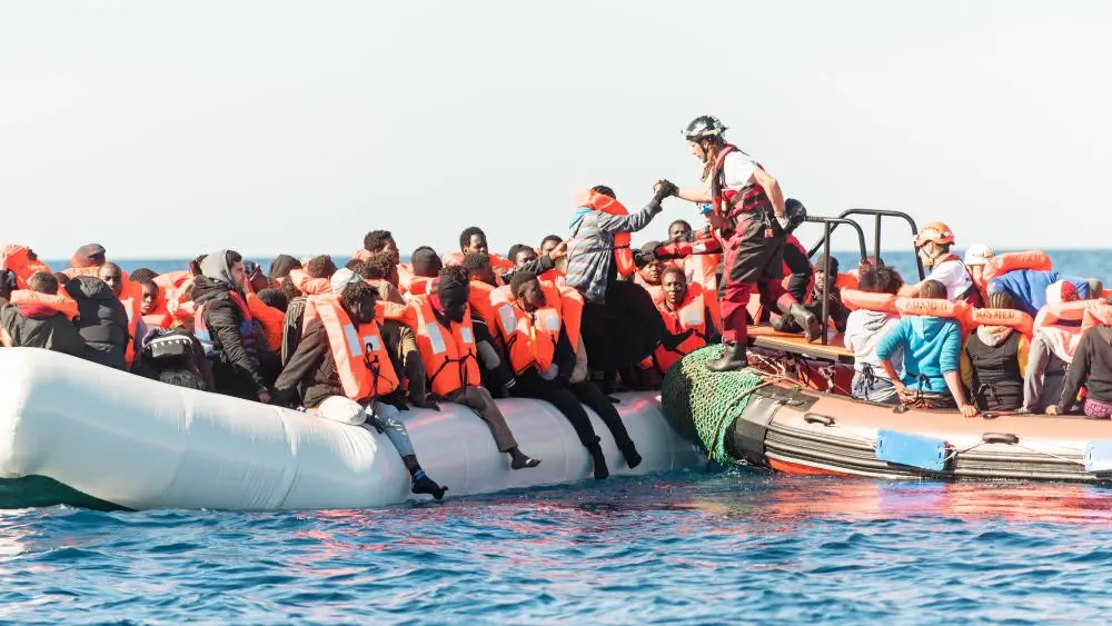 Schlauchboot mit vielen Menschen die eine Rettungsweste tragen