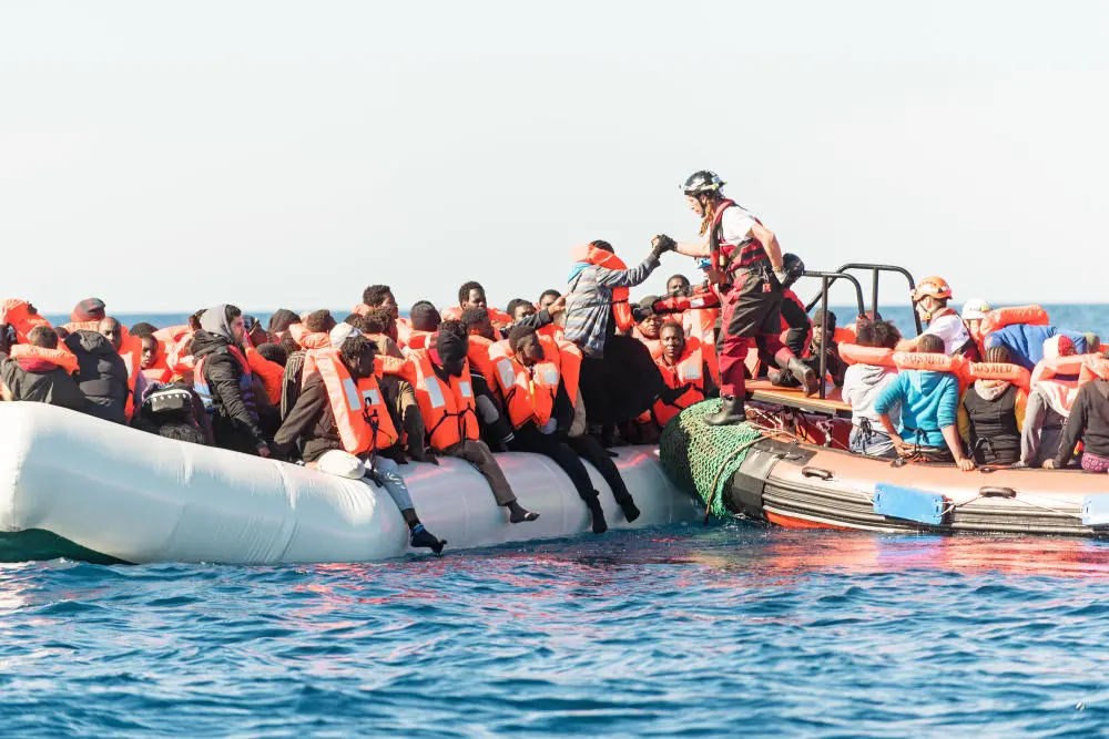 Schlauchboot mit vielen Menschen die eine Rettungsweste tragen