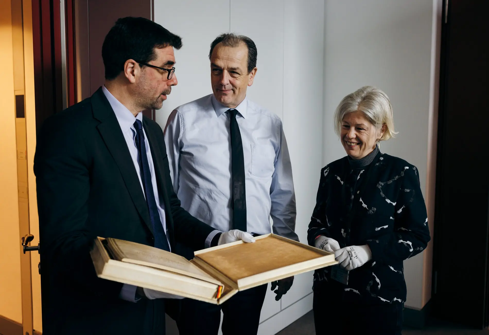 Michael Schäfer, Direktor des Deutschen Bundestages, (mitte) übergibt in seinem Büro die Urschrift des Grundgesetzes an die Parlamentsarchivarin Angela Ullmann (rechts)