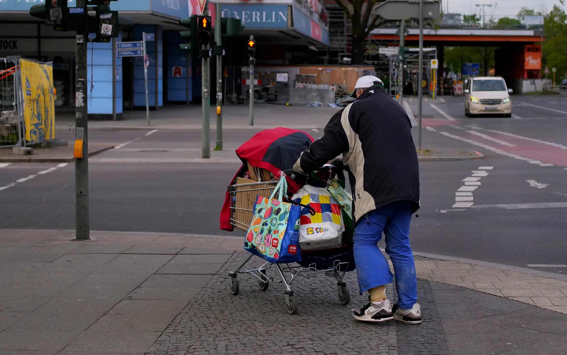 Ein wohnungsloser Mann mit einem voll beladenen Einkaufswagen auf einer Straße