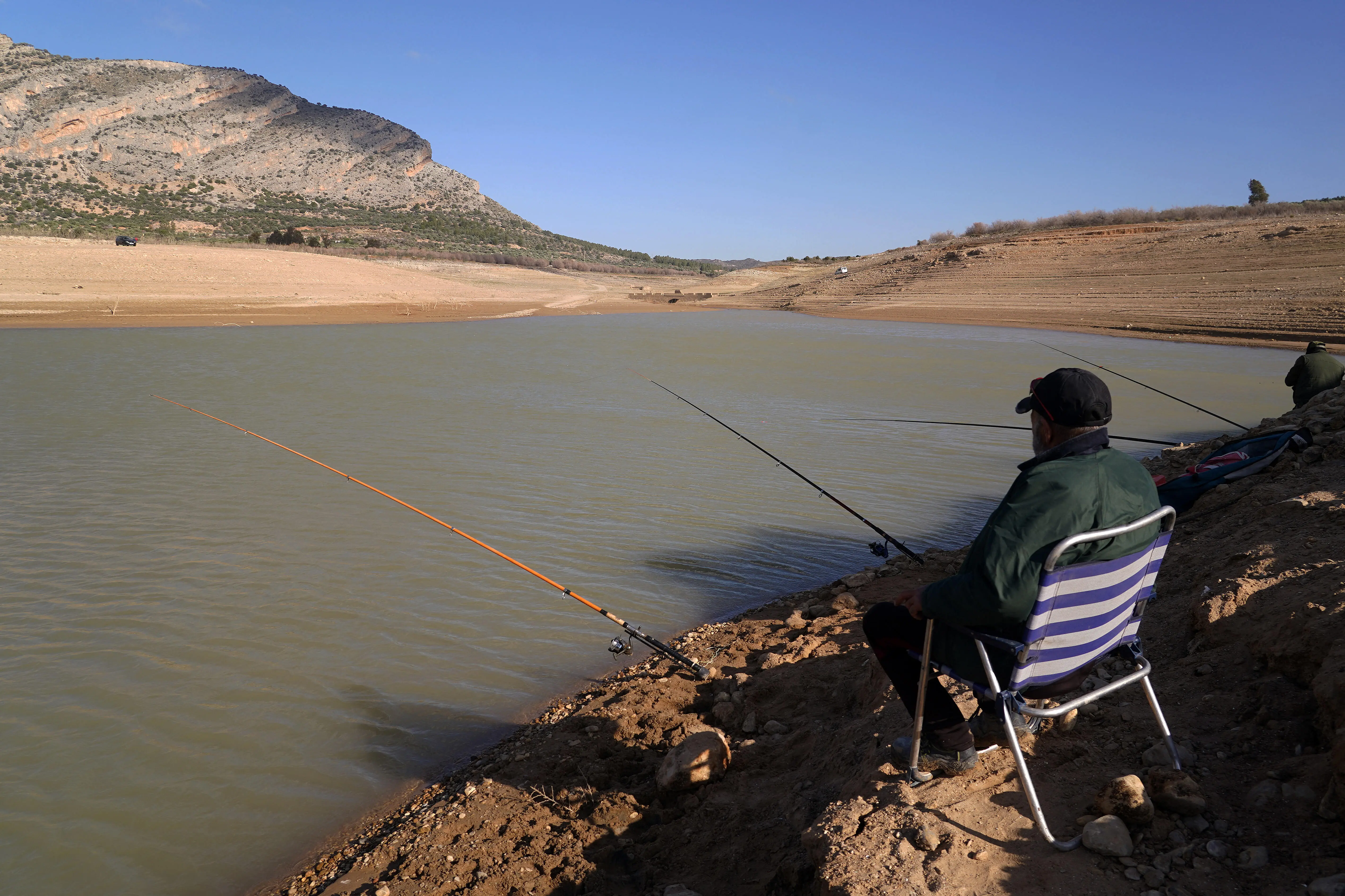 Dürre in Andalusien Zwei Angler sitzen an einem fast ausgetrockneten See in Andalusien