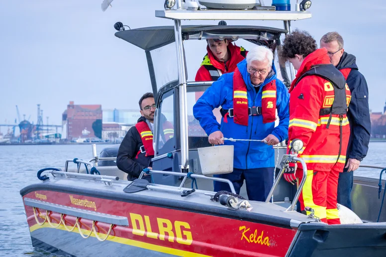 Frank-Walter Steinmeier hebt eine Boje auf ein Boot