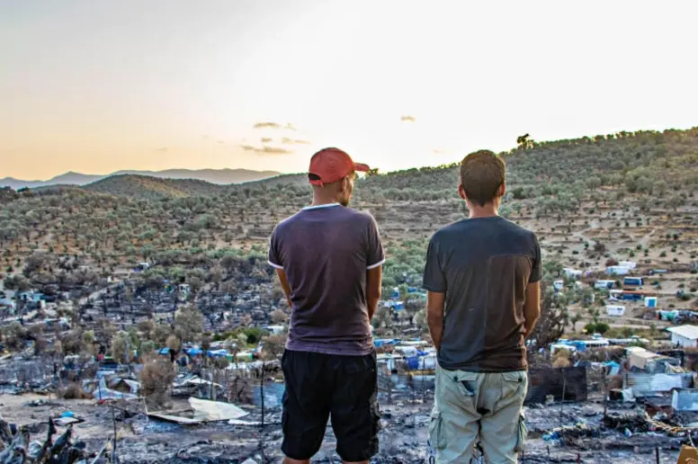 Zwei Männer stehen vor den Ruinen des abgebrannten Flüchtlingslagers in Moria