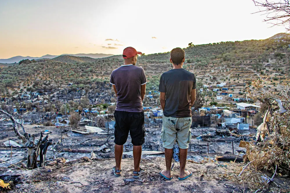 Zwei Männer stehen vor den Ruinen des abgebrannten Flüchtlingslagers in Moria auf Lesbos