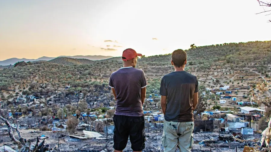 Zwei Männer stehen vor den Ruinen des abgebrannten Flüchtlingslagers in Moria