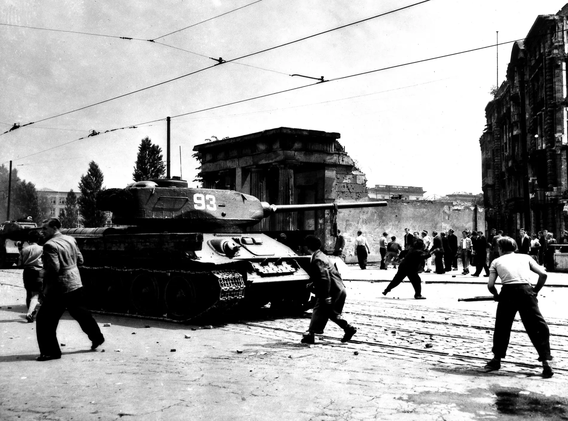 Interpretationen historischer Ereignisse Schwarz-weiß Foto Menschen werfen Steine in Richtung eines sowjetischen Panzers