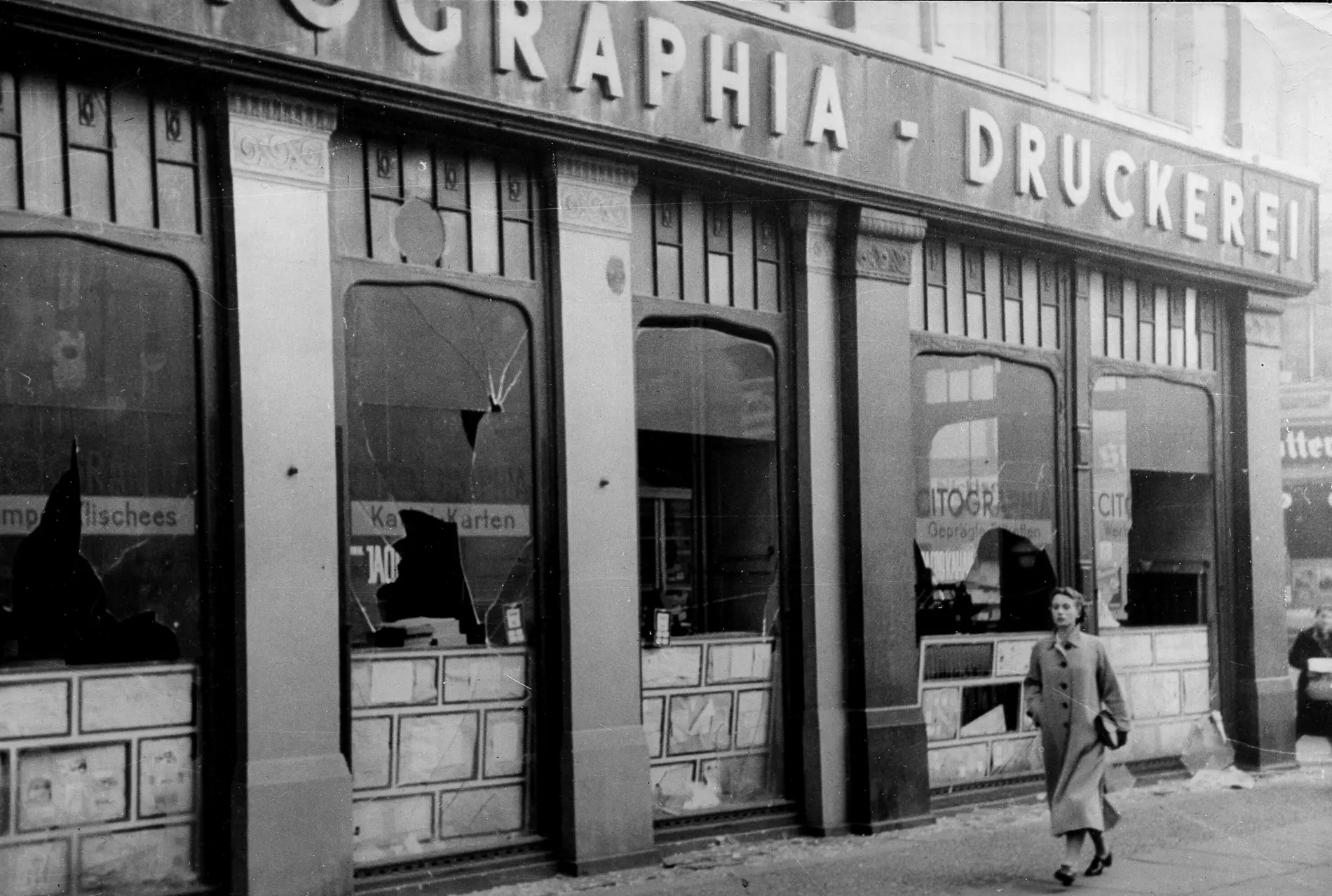 Eine Frau geht an zerbrochenen Fenstern jüdischer Geschäfte in Berlin vorbei. 