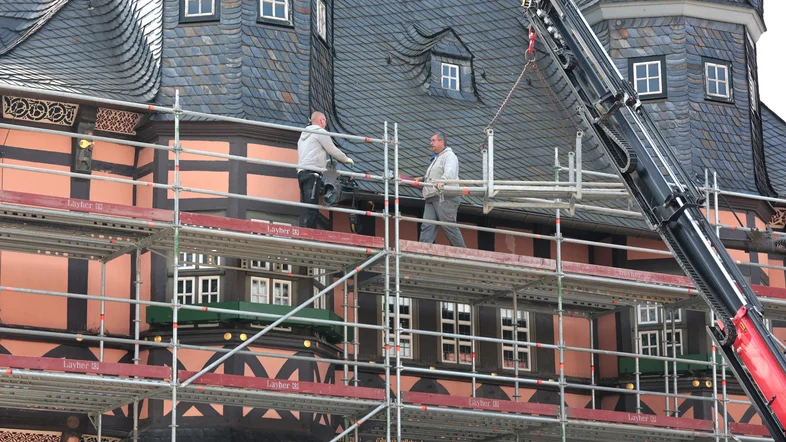 Gerüstbauer stellen an einer Rathausfassade ein Baugerüst auf