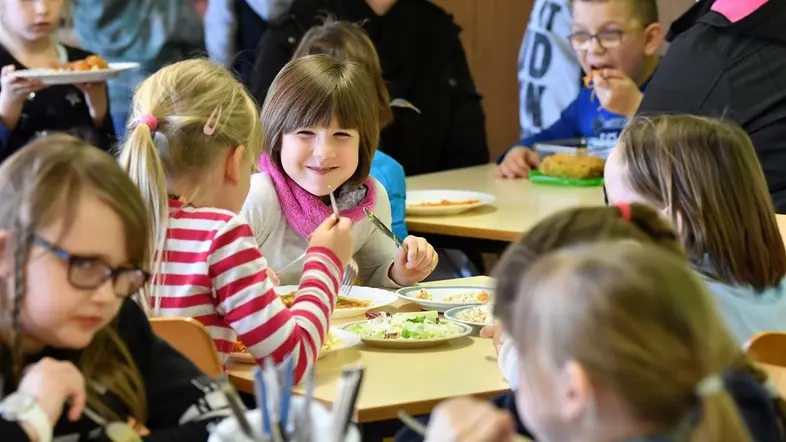 Schüler sitzen beim Mittagessen im Speiseraum einer Grundschule