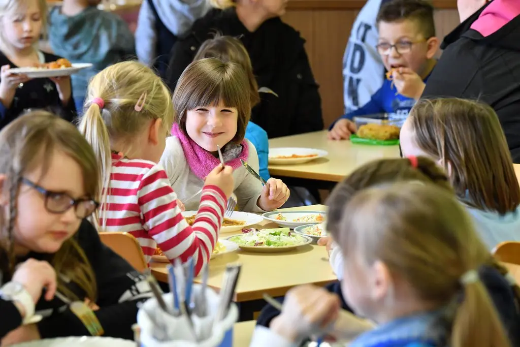 Schüler sitzen beim Mittagessen im Speiseraum einer Grundschule