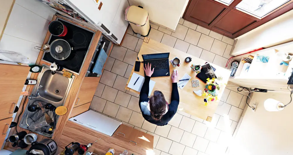 Homeoffice weiterhin angesagt Eine Frau sitzt am Esstisch in der Küche und arbeitet am Laptop.