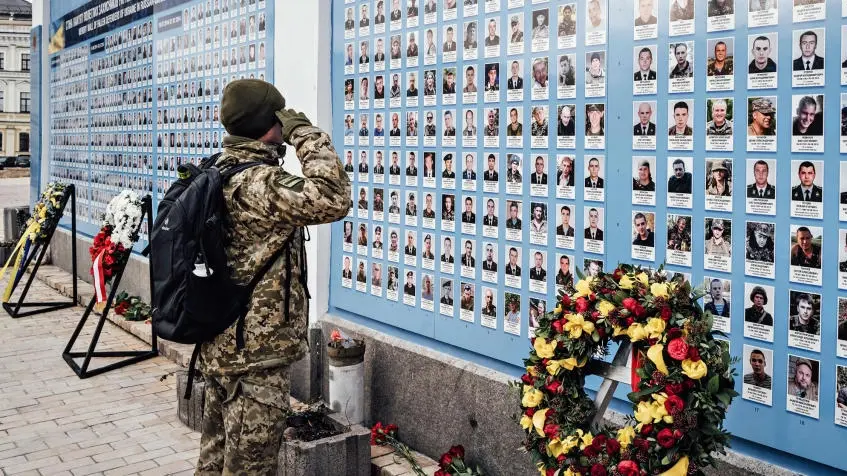 Ein Soldat salutiert vor den Bildern Gefallener.