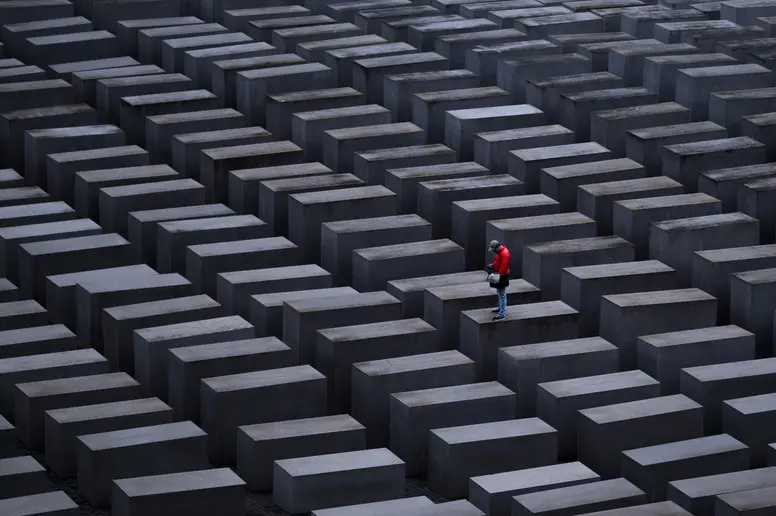 Ein Mann mit roter Jacke steht auf einer Stele am Holocaust-Mahnmal in Berlin