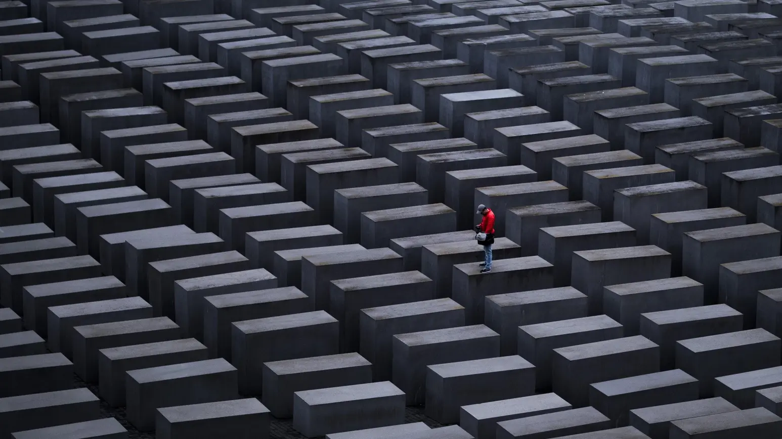 Holocaust-Mahnmal in Berlin Ein Mann mit roter Jacke steht auf einer Stele am Holocaust-Mahnmal in Berlin