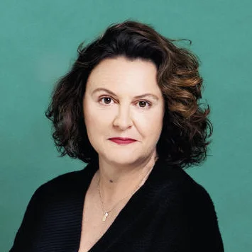 Jana Hensel sitzt auf einem Hocker vor einer grünen Wand.