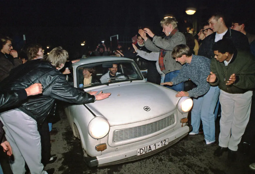 Mauerfall 1989 in Berlin Ein Trabbi wird an der Deutsch-Deutschen Grenze von Menschen begrüßt.