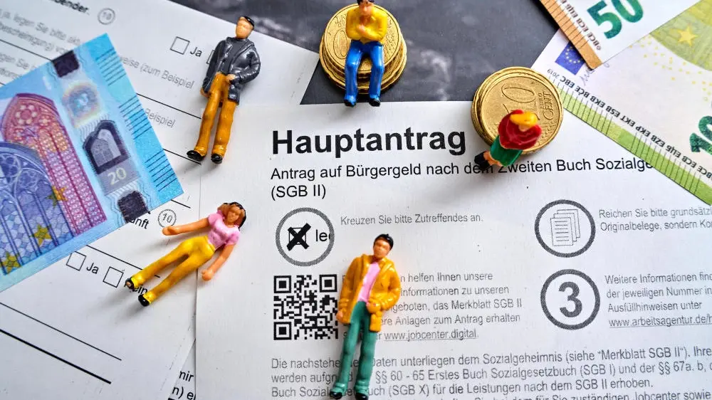 Aktuelle Stunde zum Bürgergeld Bürgergeld-Hauptantrag mit Euro Geldscheinen und Menschen Figuren