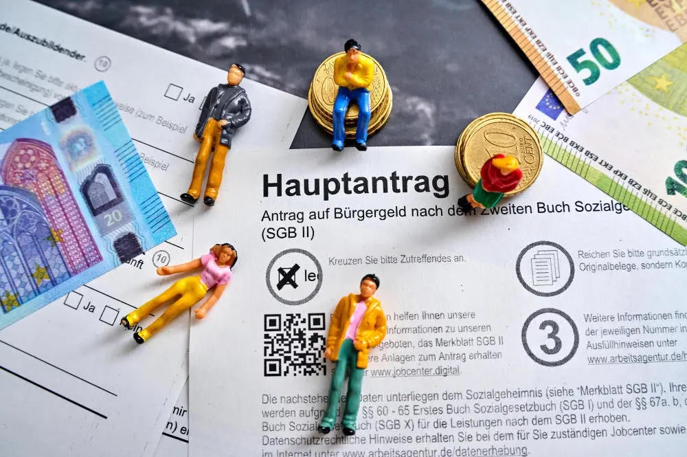 Aktuelle Stunde zum Bürgergeld Bürgergeld-Hauptantrag mit Euro Geldscheinen und Menschen Figuren
