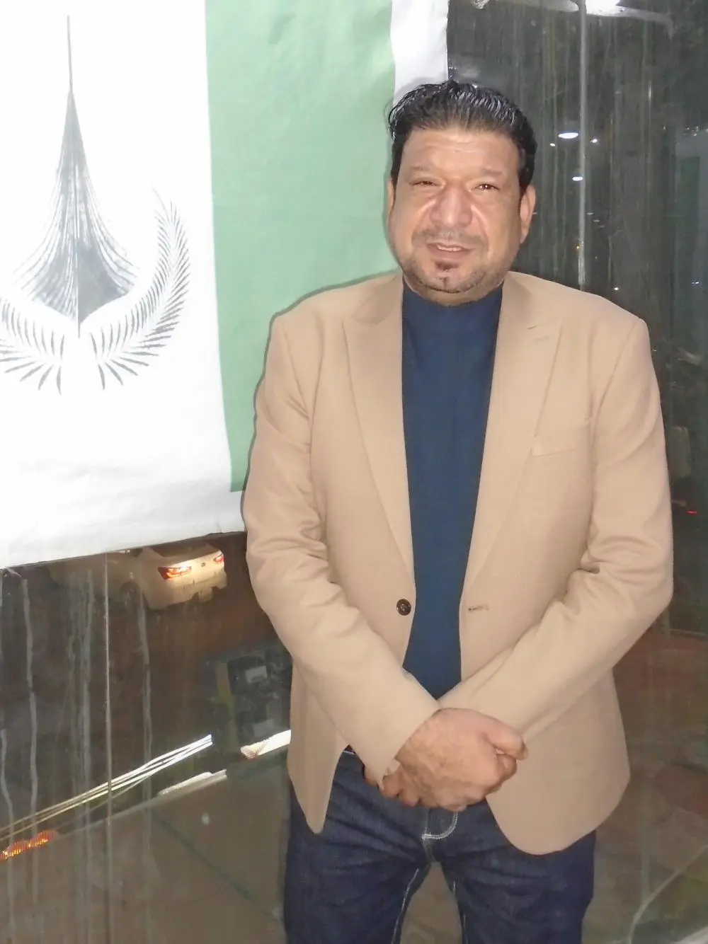 Kandidat Naqib Al Laebie steht vor einer Fahne
