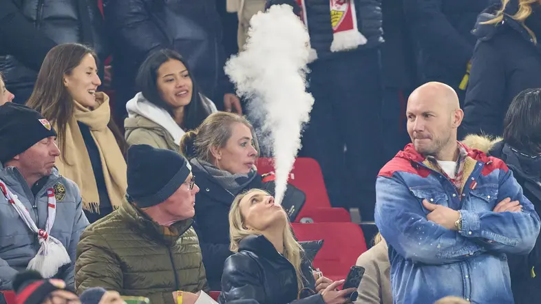 Raucherin inmitten von Fußballfans im Stadium.