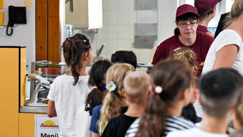 Schüler stehen in der Schlange vor der Essensausgabe in der Mensa