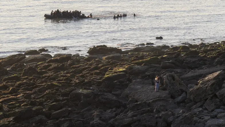 Zu sehen sind viele Menschen auf einem Schlauchboot, das vom Ufer aus ins Meer fährt. 