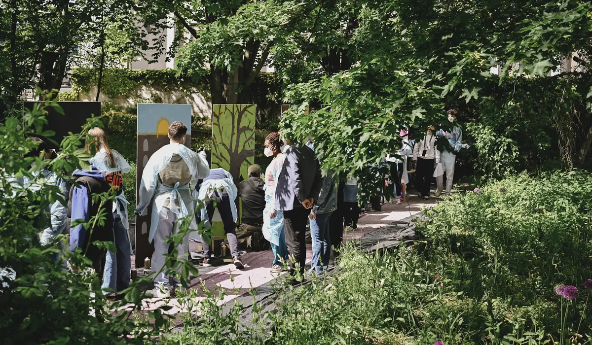 Mehrere Menschen stehen im Wald vor besprühten Wänden
