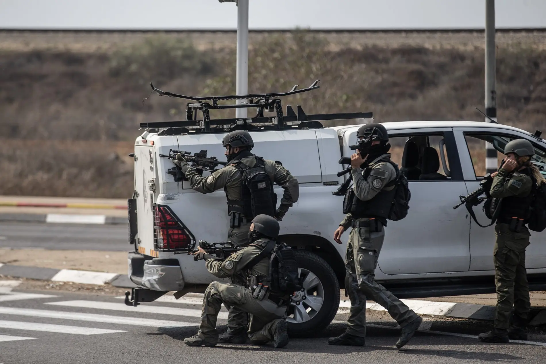 Bewaffnete israelische Soldaten suchen einen Tag nach dem Angriff der Hamas auf Israel Schutz hinter einem Fahrzeug. 