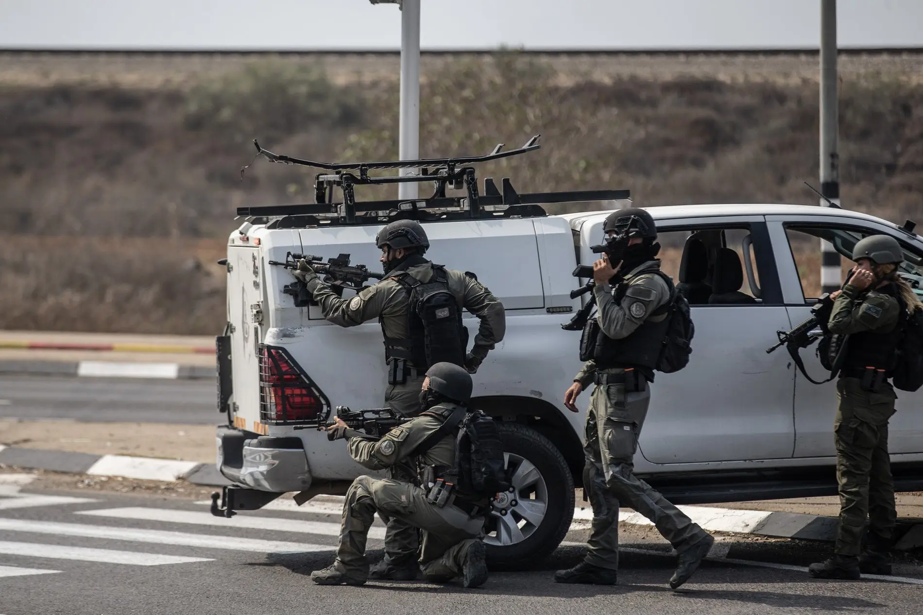 Israelische Soldaten suchen Schutz hinter einem Auto Bewaffnete israelische Soldaten suchen einen Tag nach dem Angriff der Hamas auf Israel Schutz hinter einem Fahrzeug.
