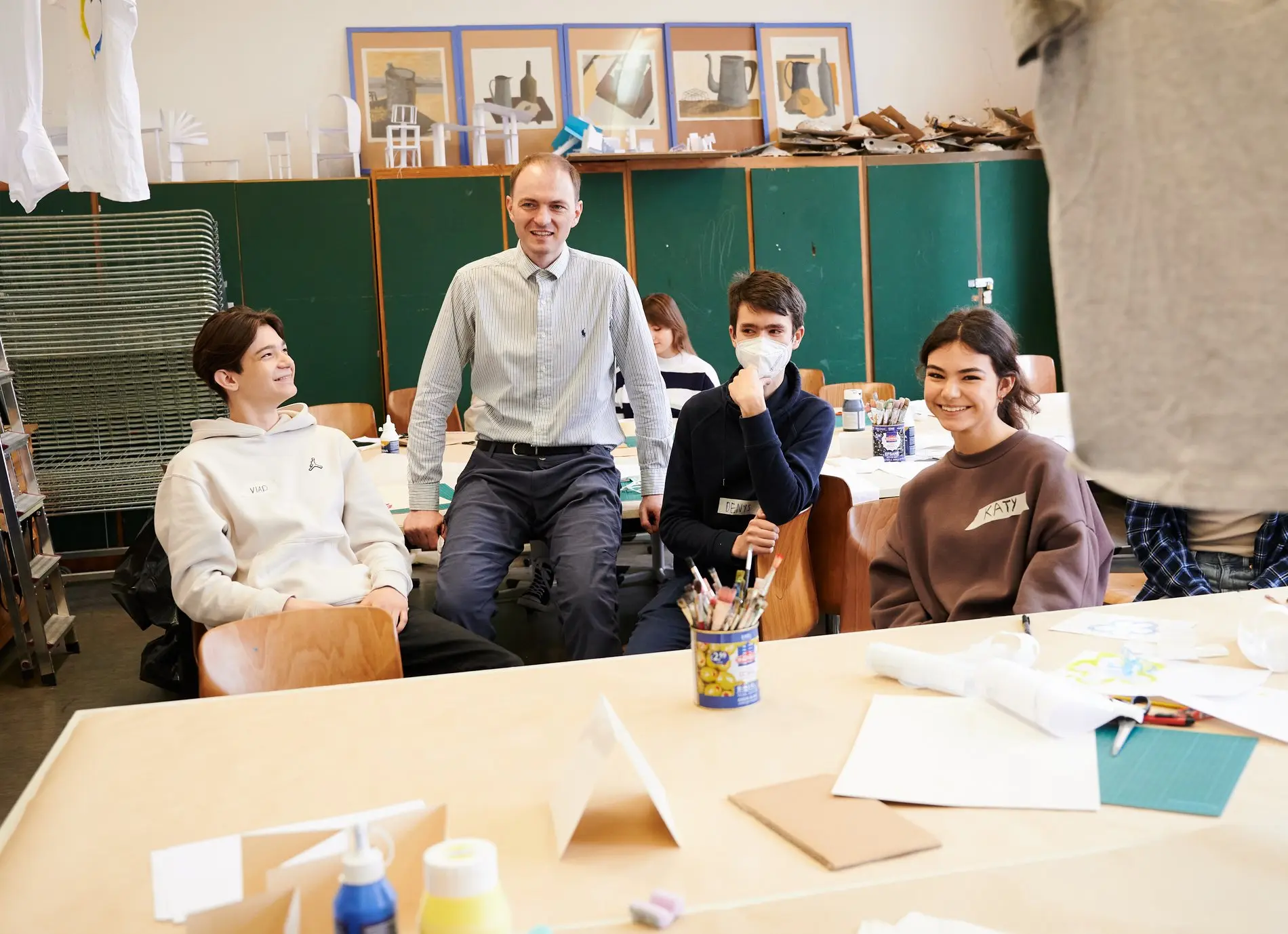 Ein Lehrer sitzt in einer Willkommensklasse zwischen Jugendlichen