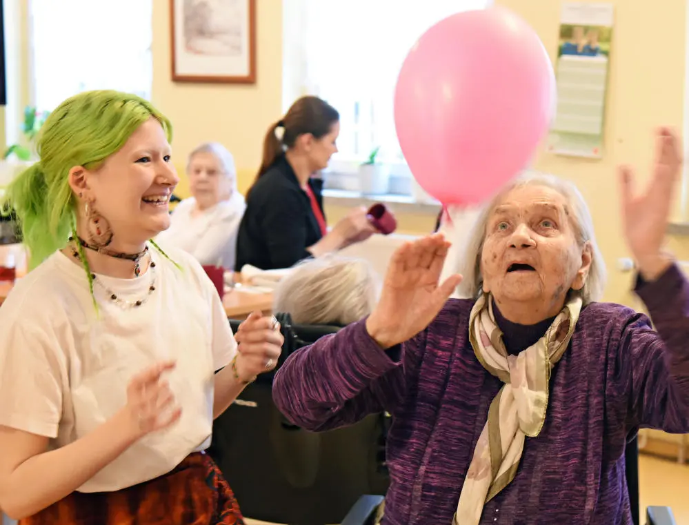 Eine ältere Frau spielt mit einem Ballon
