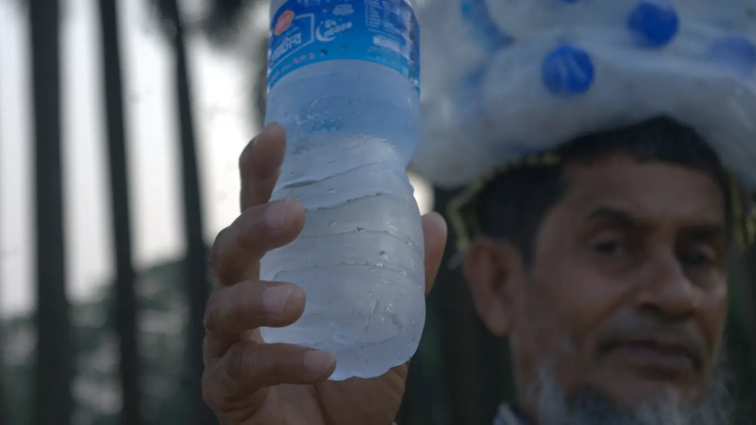 Trinkwasser in Entwicklungsländern Ein Mann hält eine kalte Wasserflasche in die Kamera