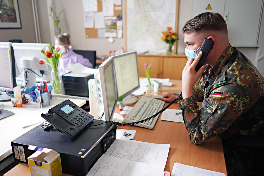 Soldat in Uniform telefoniert am Schreibtisch.