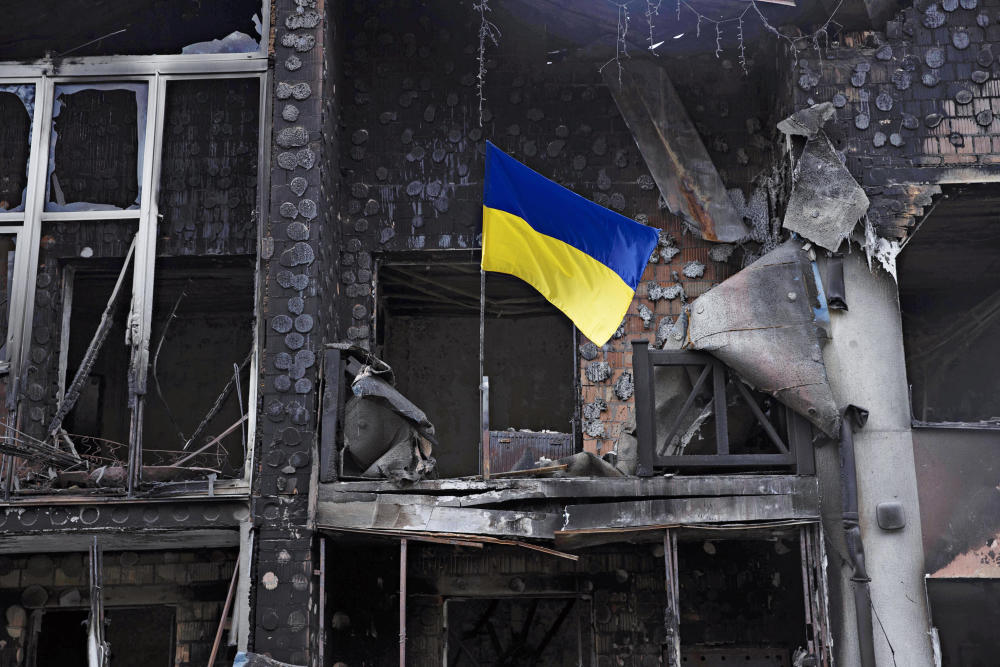 In den Trümmern eines zerstörten Gebäudes weht eine ukrainische Flagge